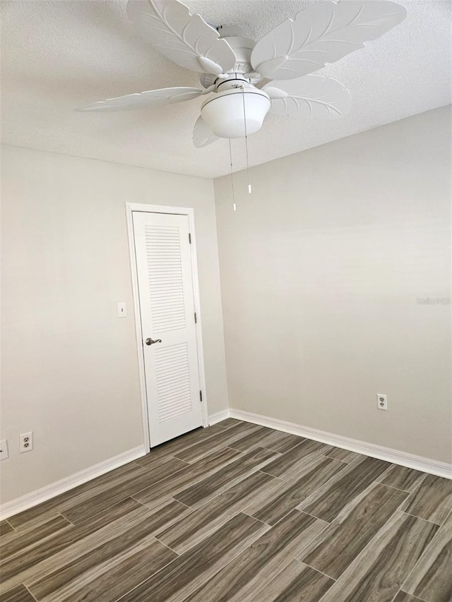 unfurnished room featuring a textured ceiling, a ceiling fan, baseboards, and wood tiled floor