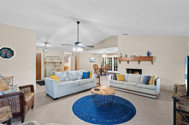 tiled living room with ceiling fan, brick wall, vaulted ceiling, and a fireplace