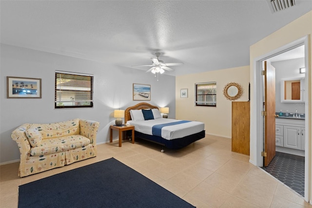 tiled bedroom featuring connected bathroom, ceiling fan, a textured ceiling, and sink