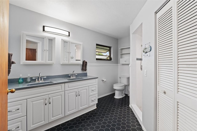 bathroom with a textured ceiling, toilet, vanity, wooden walls, and tile patterned flooring