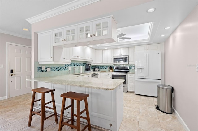 kitchen featuring kitchen peninsula, white cabinets, backsplash, ornamental molding, and stainless steel appliances