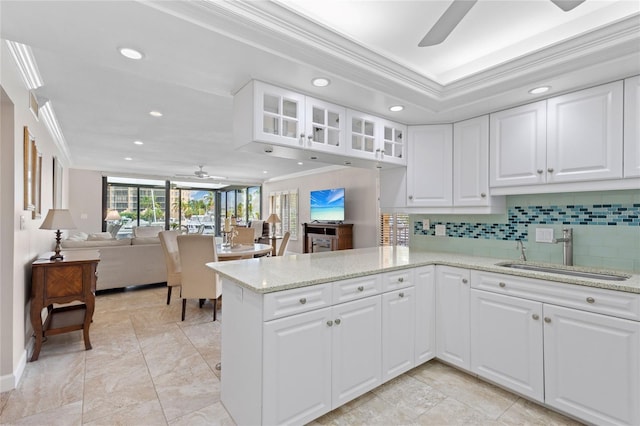 kitchen featuring ornamental molding, kitchen peninsula, white cabinetry, and sink