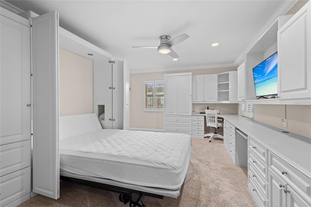 bedroom featuring built in desk, ceiling fan, crown molding, and light colored carpet