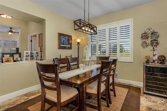 dining area with wood-type flooring, beverage cooler, and ceiling fan with notable chandelier