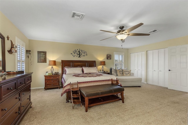 carpeted bedroom featuring ceiling fan and multiple closets