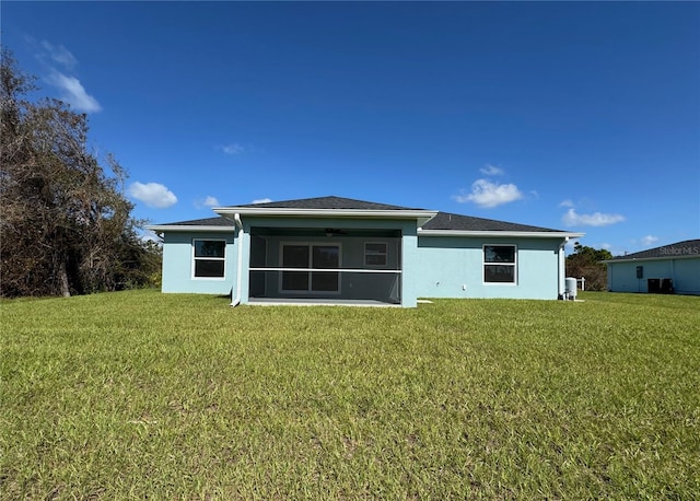 rear view of property featuring ceiling fan and a lawn