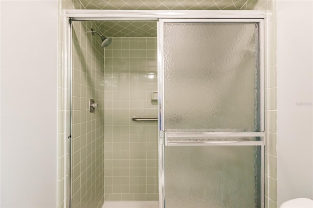 bathroom featuring a shower with door and toilet