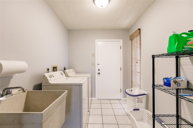 clothes washing area featuring sink, a textured ceiling, separate washer and dryer, and light tile patterned floors