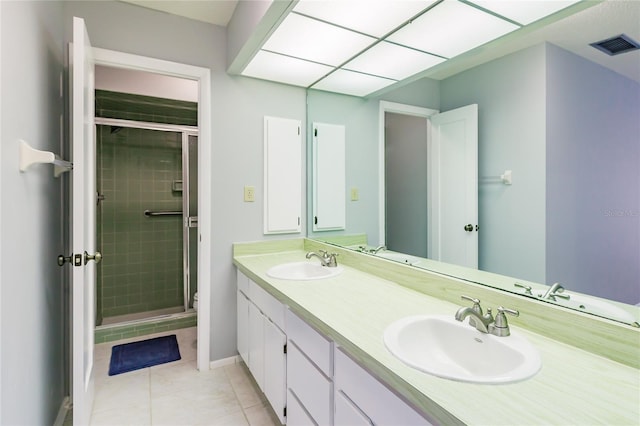 bathroom featuring a shower with door, vanity, and tile patterned floors