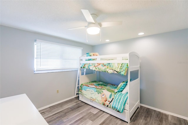 bedroom with hardwood / wood-style floors, a textured ceiling, and ceiling fan