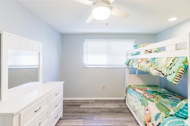 bedroom with ceiling fan, hardwood / wood-style flooring, a textured ceiling, and multiple windows