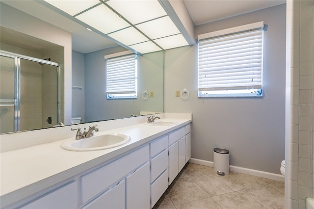 bathroom featuring toilet, vanity, plenty of natural light, and a shower with door