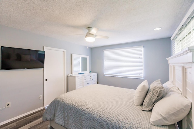 bedroom featuring ceiling fan, a textured ceiling, multiple windows, and dark hardwood / wood-style floors