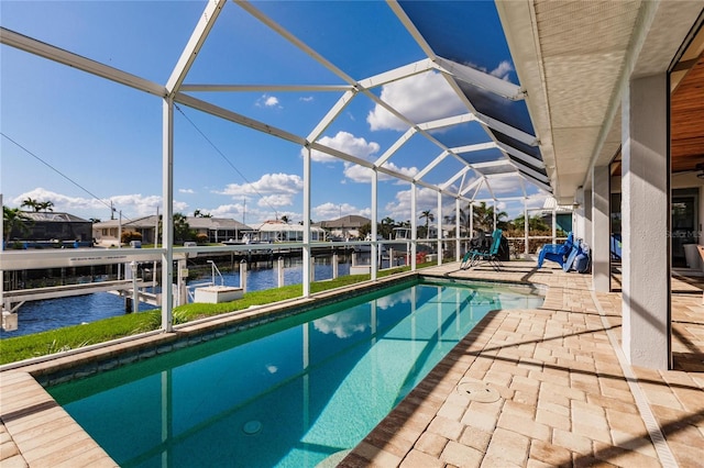 view of pool featuring a patio, a water view, glass enclosure, and a boat dock