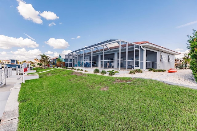 back of property featuring a yard and glass enclosure