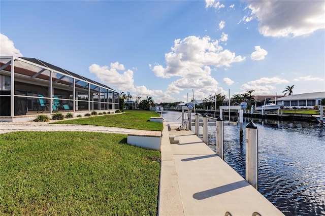 view of dock with glass enclosure, a water view, and a lawn