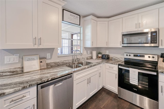 kitchen with sink, a textured ceiling, dark hardwood / wood-style flooring, white cabinetry, and stainless steel appliances