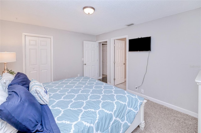 carpeted bedroom featuring a closet and a textured ceiling