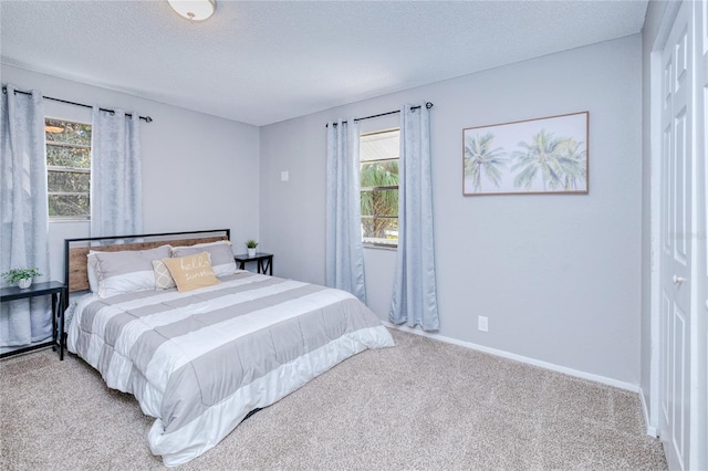 carpeted bedroom featuring multiple windows and a textured ceiling