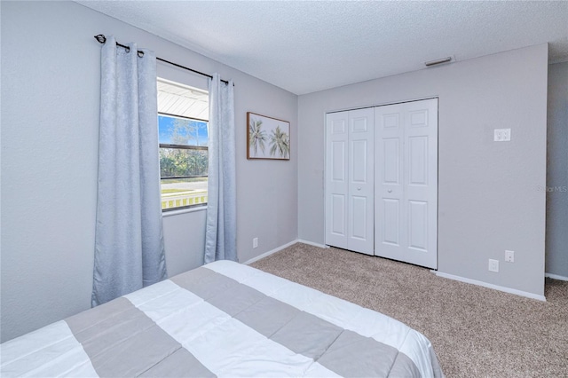 carpeted bedroom with a closet and a textured ceiling