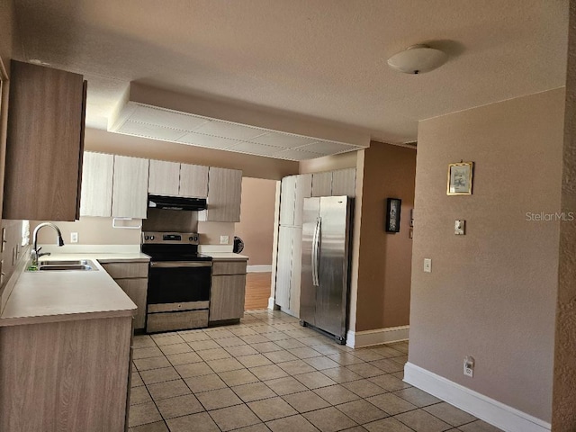 kitchen with electric stove, stainless steel refrigerator, light tile patterned floors, light brown cabinets, and sink