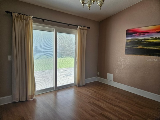 unfurnished room with hardwood / wood-style flooring and an inviting chandelier