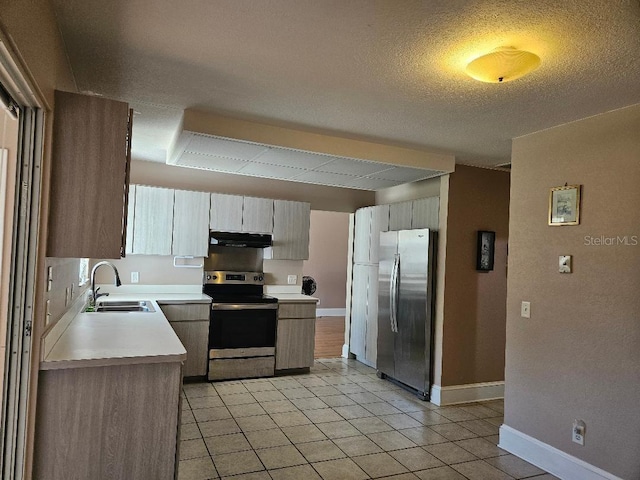 kitchen with a textured ceiling, appliances with stainless steel finishes, sink, and light tile patterned floors