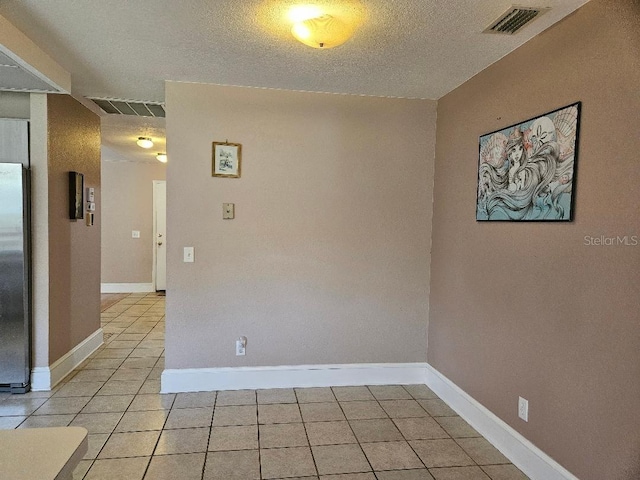 tiled spare room featuring a textured ceiling