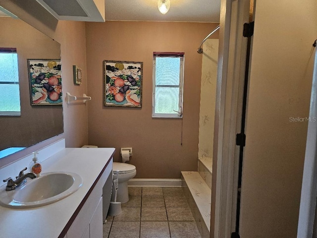 bathroom with a wealth of natural light, tile patterned flooring, vanity, and toilet