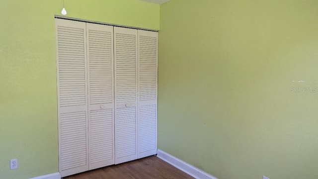 unfurnished bedroom with dark wood-type flooring and a closet