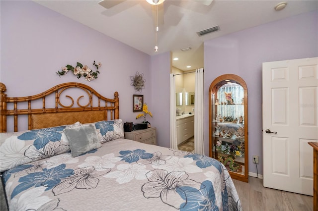 bedroom with light hardwood / wood-style floors, ensuite bathroom, and ceiling fan