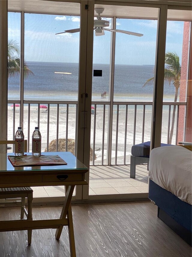 bedroom with a water view, a view of the beach, and wood-type flooring