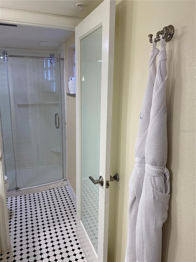 bathroom featuring a shower with door, toilet, and tile patterned flooring