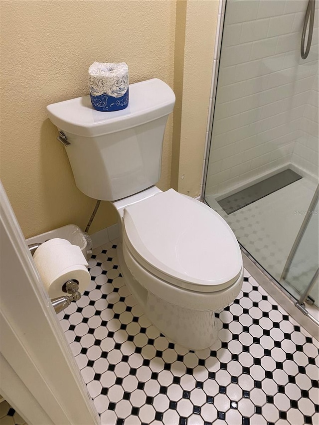 bathroom with toilet and a shower with shower door