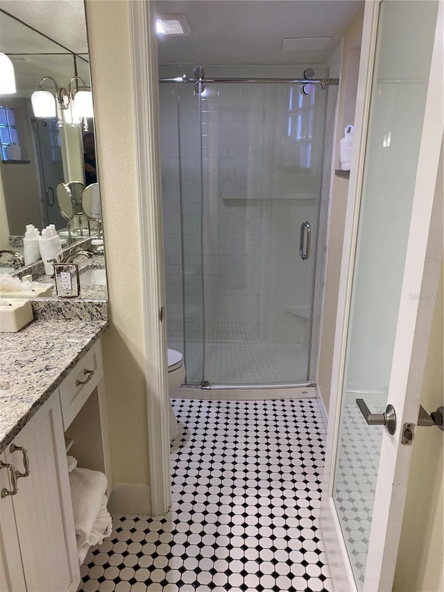 bathroom with vanity, an enclosed shower, toilet, and tile patterned floors