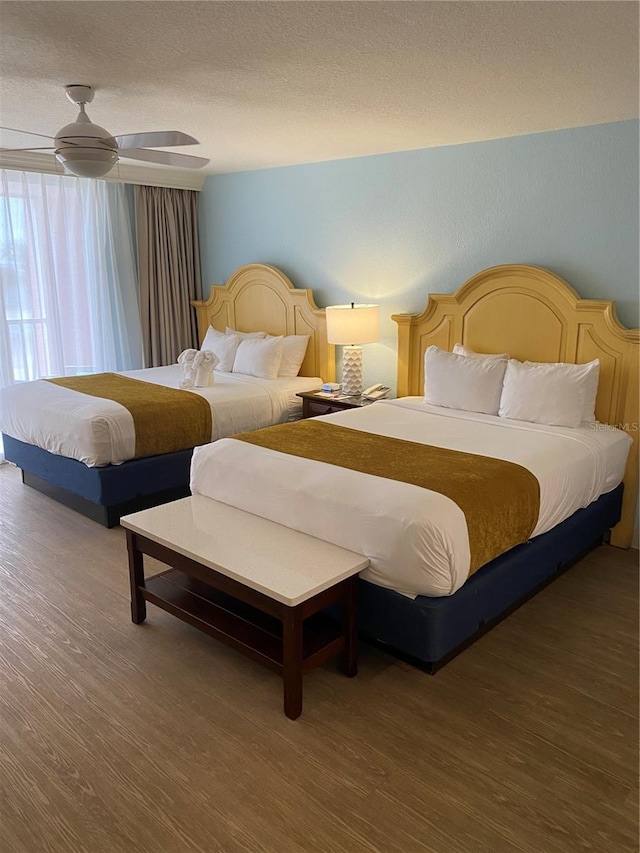 bedroom with a textured ceiling, wood-type flooring, and ceiling fan