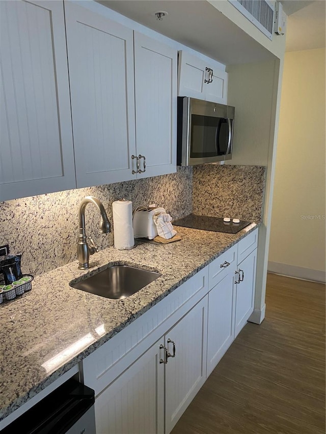 kitchen featuring sink, white cabinetry, dark wood-type flooring, light stone counters, and decorative backsplash