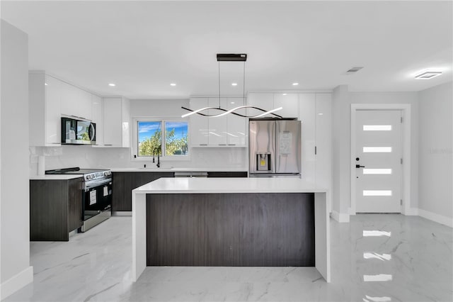 kitchen featuring dark brown cabinets, appliances with stainless steel finishes, decorative light fixtures, and white cabinets