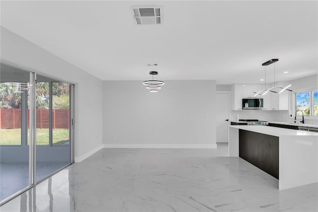 kitchen with stainless steel appliances, backsplash, decorative light fixtures, an inviting chandelier, and white cabinetry