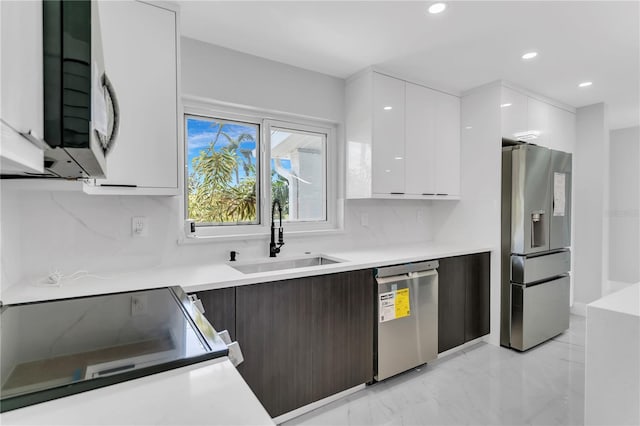 kitchen with backsplash, sink, appliances with stainless steel finishes, and white cabinetry