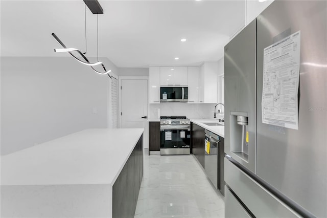 kitchen with decorative backsplash, hanging light fixtures, stainless steel appliances, sink, and white cabinets