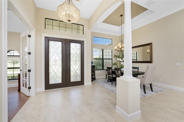 entrance foyer featuring french doors, a towering ceiling, a chandelier, a tray ceiling, and light hardwood / wood-style flooring