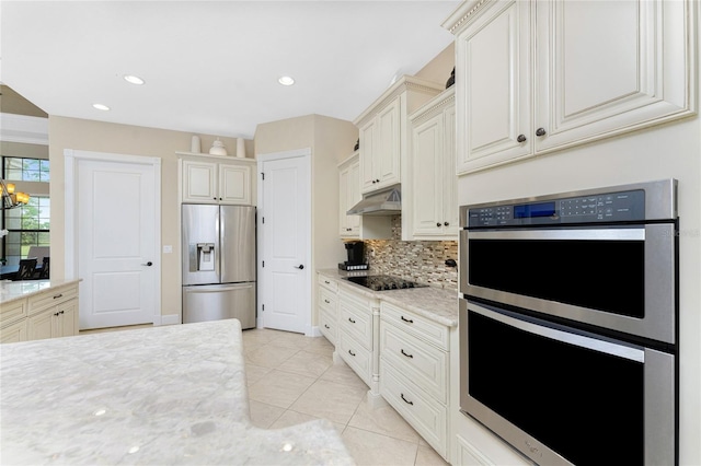 kitchen featuring tasteful backsplash, appliances with stainless steel finishes, light stone counters, and light tile patterned flooring