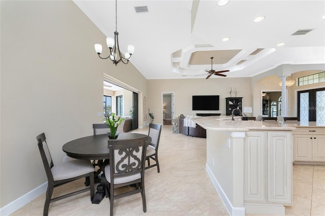 dining room with ceiling fan with notable chandelier, a healthy amount of sunlight, sink, and decorative columns