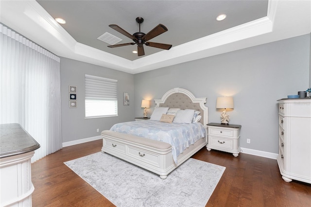 bedroom with ornamental molding, dark wood-type flooring, ceiling fan, and a raised ceiling