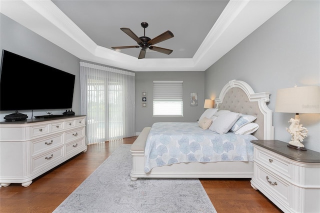 bedroom featuring access to outside, dark hardwood / wood-style floors, ceiling fan, and a tray ceiling