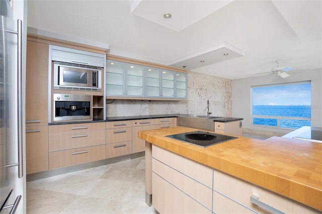 kitchen with stainless steel appliances, wood counters, tasteful backsplash, modern cabinets, and glass insert cabinets