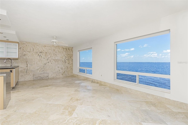 spare room with a ceiling fan, a water view, and a sink