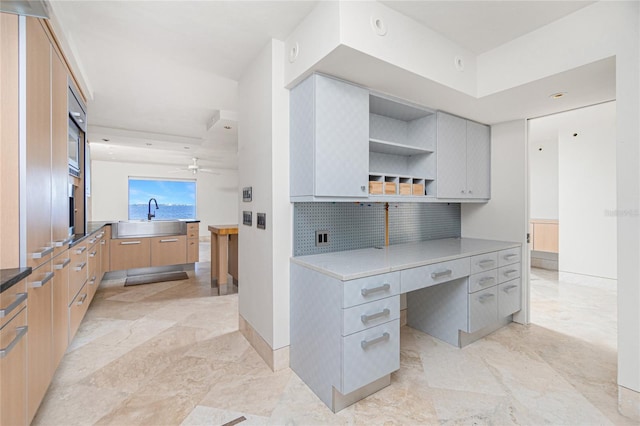 interior space with ceiling fan, tasteful backsplash, light brown cabinetry, and sink