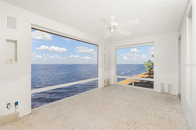 carpeted spare room featuring a water view, ceiling fan, and a healthy amount of sunlight